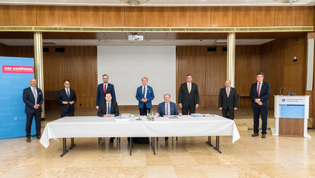 Neun Herren unterzeichnen einen Kaufvertrag in der Handwerkskammer des Saarlandes