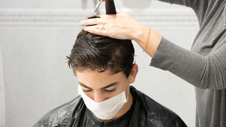 Ein Junge mit Mundschutz beim Friseur